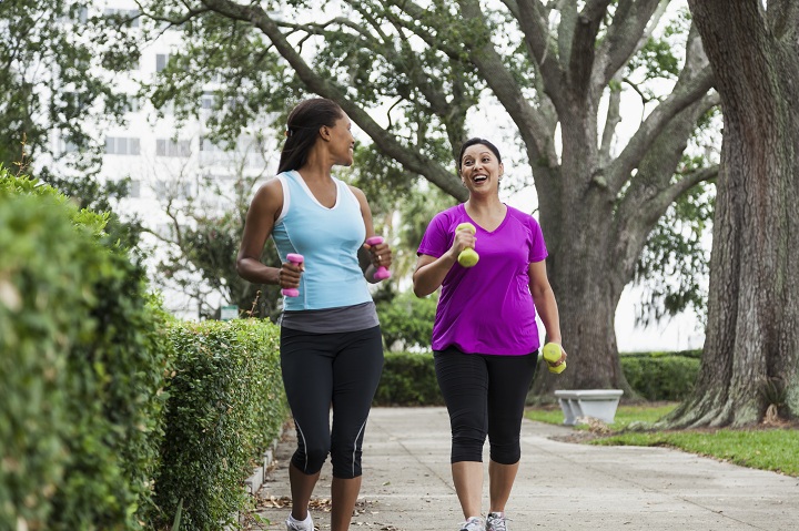 Multi-ethnic women (30s, 40s) exercising in park, power walking.